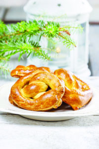 Christmas pretzel under fir branch. White candle in iron lantern